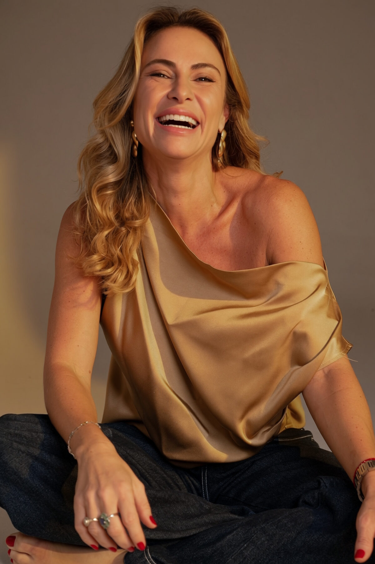 Maria Flavia sentada, sorrindo, em blusa dourada